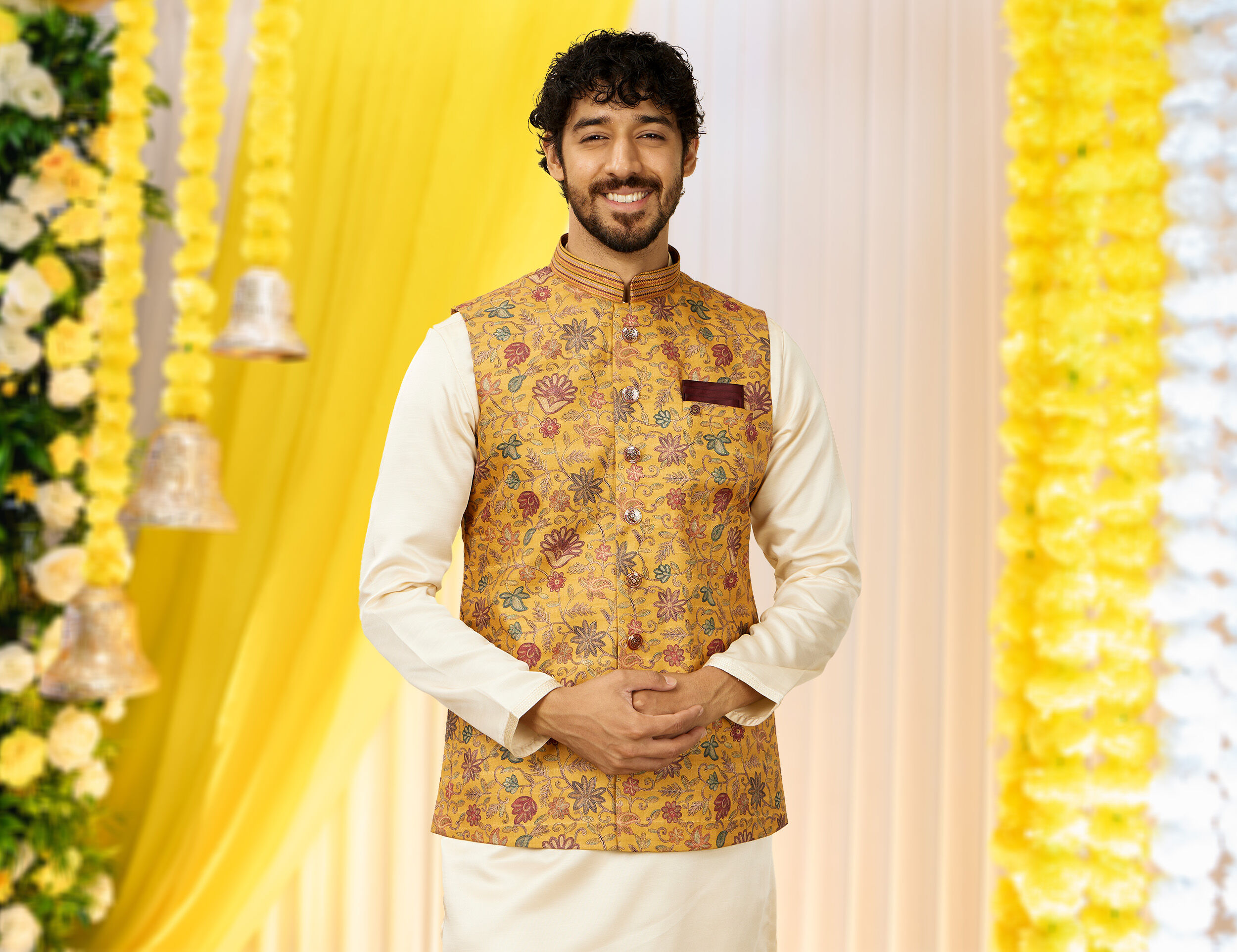 A groom wearing white kurta with printed yellow jackeyt on his haldi ceremony